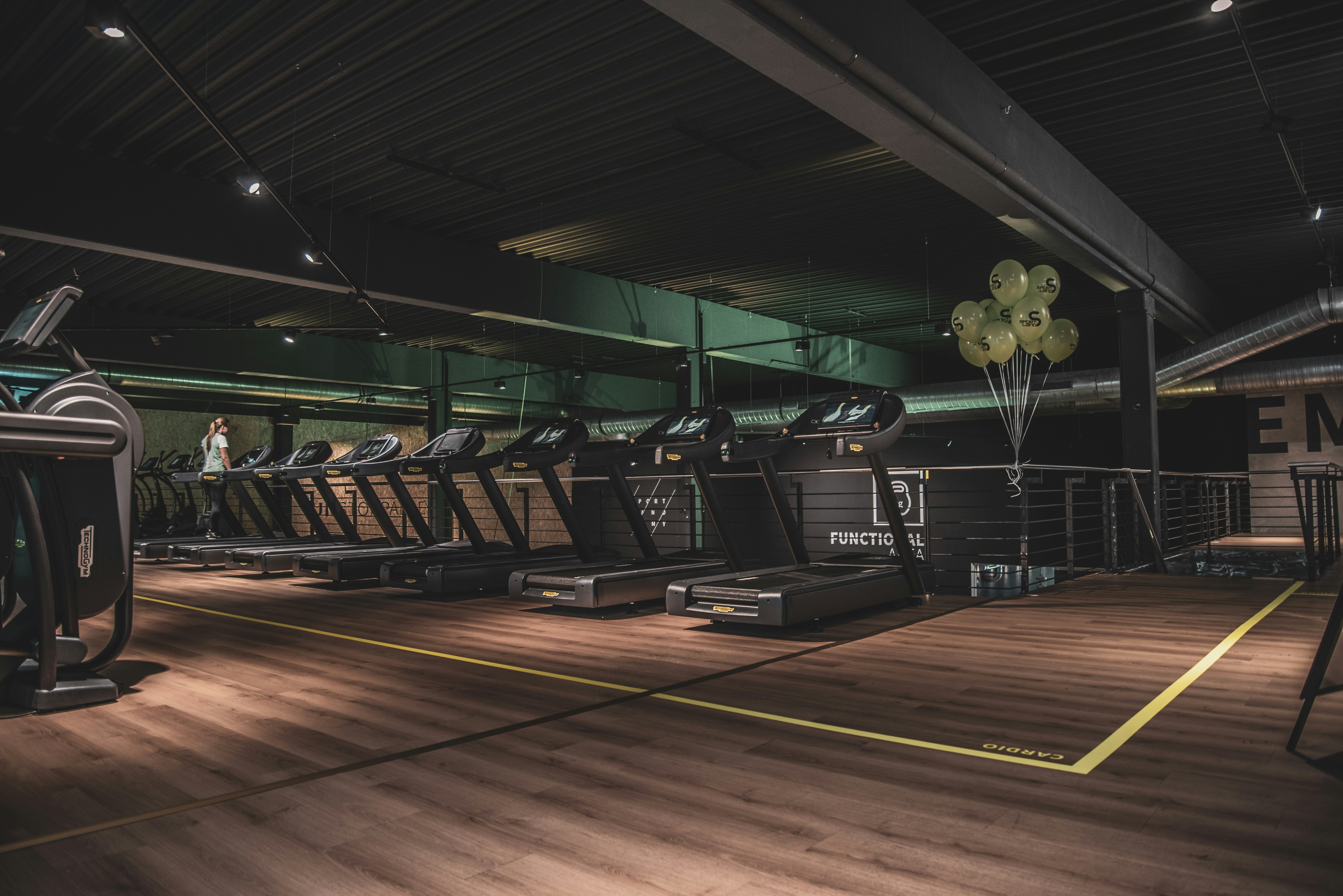 ATLAS cardio deck with commercial machines, daylight, and green walls
